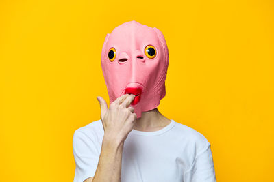 Portrait of woman wearing mask against yellow background