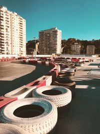 Tires arranged on road against clear blue sky during sunny day