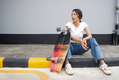 Young woman looking down while sitting on wall