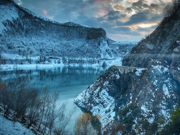 Scenic view of lake by snowcapped mountains against sky