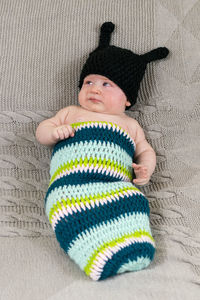 High angle view of cute baby girl wearing knitted clothing on bed