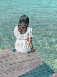 Rear view of woman sitting on swimming pool