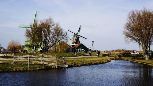 Traditional windmill by river against sky