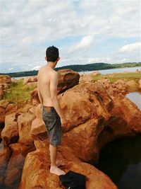 Rear view of shirtless man standing on beach