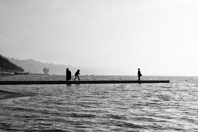 People standing by sea on pier