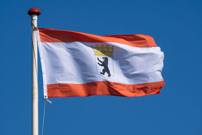 Low angle view of flag against clear blue sky