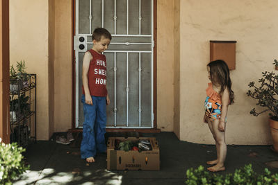 Children standing by csa farmers box full of produce on front porch