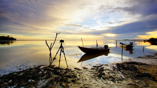 Boat moored in sea against sky during sunset