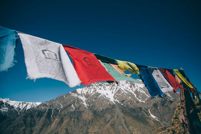 Low angle view of flags against clear blue sky