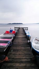 Boats moored by pier against sky