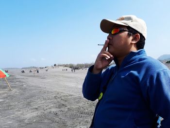 Man wearing sunglasses standing against clear sky