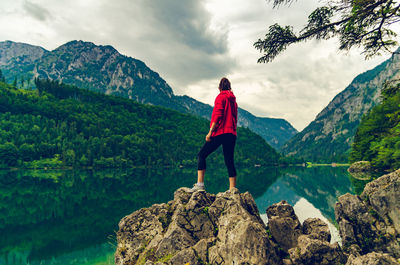 Rear view of man standing on rock looking at mountains