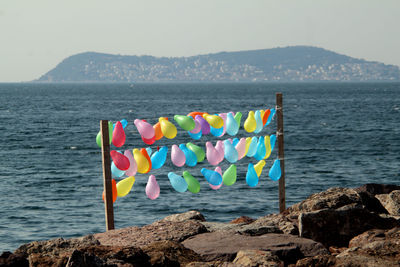 Multi colored umbrellas on rock by sea against sky