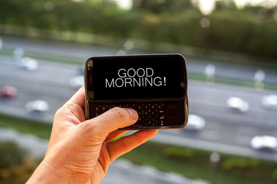 Cropped hand typing good morning text in mobile phone