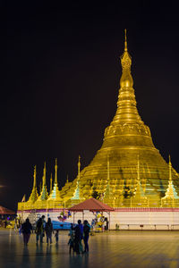 People at temple against sky at night