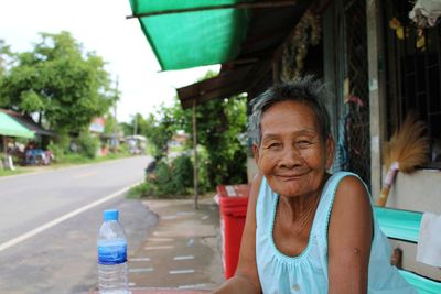 Portrait of woman with bottle outside house