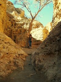 Low angle view of woman standing on rock against sky