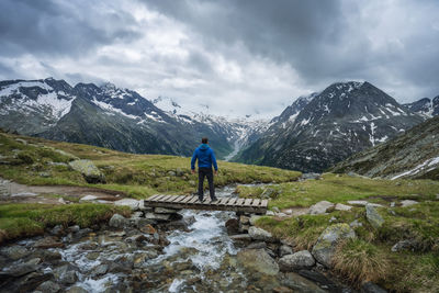 Rear view of man walking on mountain against sky