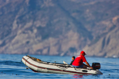 Man on boat in sea against mountains