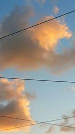 Low angle view of power lines against sky during sunset
