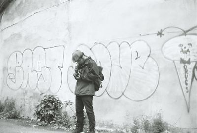 Full length of man standing against graffiti wall