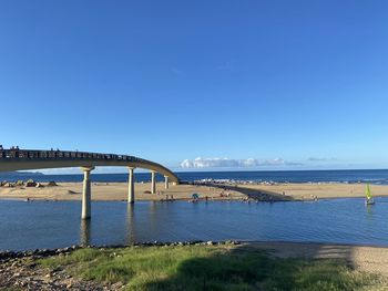 Bridge over sea against clear blue sky