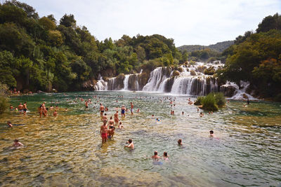 People enjoying in river against waterfall