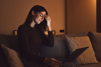 Young woman sitting on sofa at home