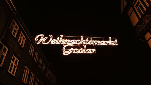 Low angle view of illuminated sign in city at night