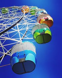 Low angle view of ferris wheel against clear blue sky