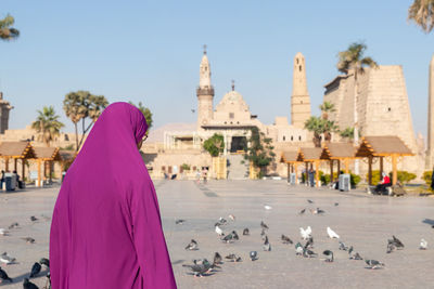 Unrecognizable muslim woman with veils walking through a typical square of her city with traditional