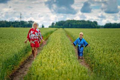 Mother and son walking by plants on field