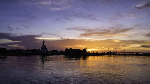 Scenic view of river against cloudy sky during sunset