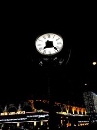 Low angle view of illuminated clock at night