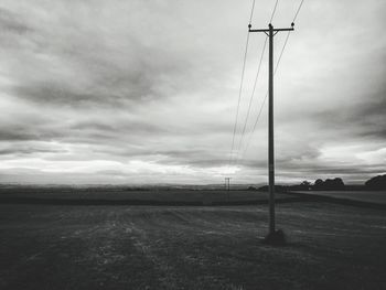 Electricity pylon on field against sky