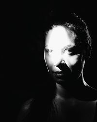 Close-up portrait of mid adult woman against black background
