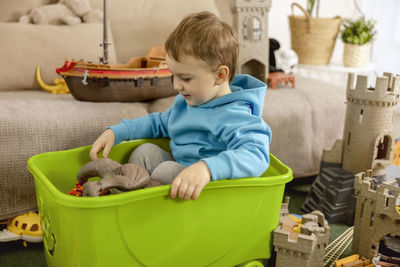 Little caucasian boy with blue hoodie playing with colourful toys at home. child having fun. 