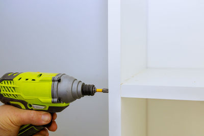 Close-up of person working on shelves by wall