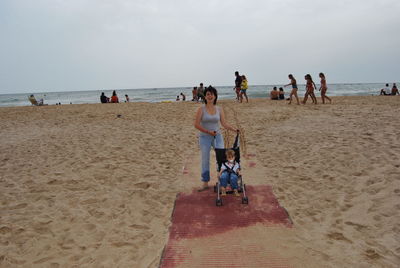 Mother standing with son at sandy beach