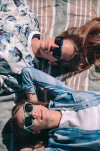 High angle view of friends wearing sunglasses while lying on blanket in forest