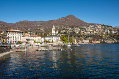 Buildings by sea against clear blue sky