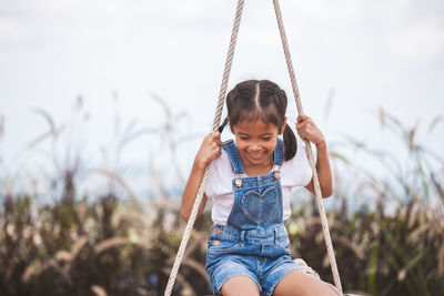 Cheerful girl swinging at playground