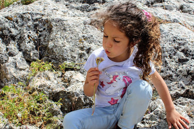 Cute girl sitting on rock