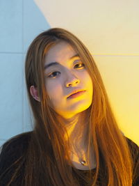 Close-up portrait of a beautiful young woman against wall