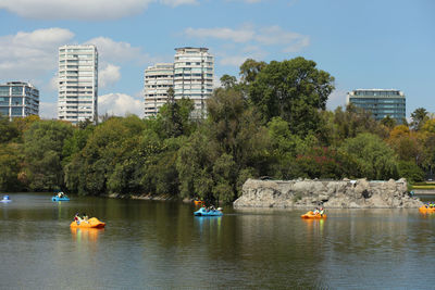 Boats in lake by city against sky