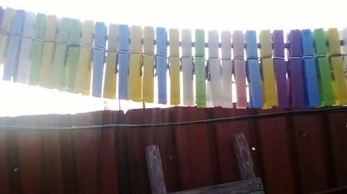 Low angle view of clothespins hanging on clothesline against sky