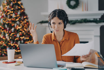 Businesswoman holding document while talking on video conference