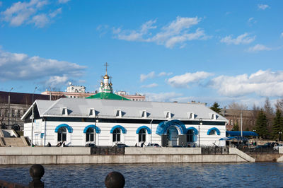 Buildings at waterfront against cloudy sky