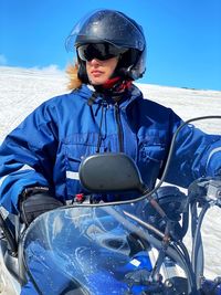 Mature woman wearing helmet riding motorcycle on snowy land