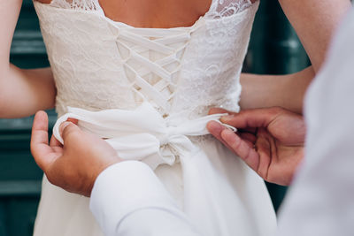 The groom tightens the corset to the bride on the wedding dress